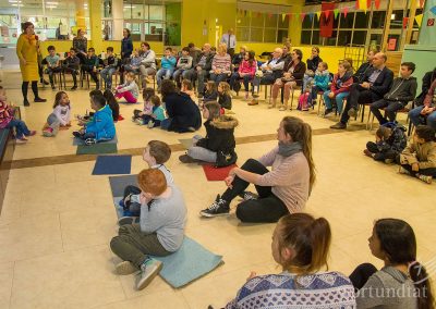 Children and adults sit in a large room and listen to a speaker - Helping children in Germany