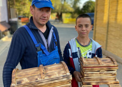 Mann und Junge halten zwei fertige, selbstgebaute Holzkisten in Händen