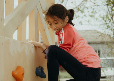 Kind klettert an einer kleinen Wand mit Kletterhilfen