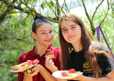 Two girls are happy about pizza and fresh tomatoes