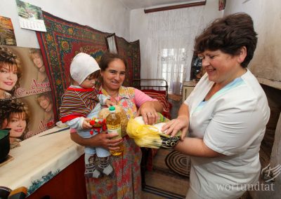 one woman presents another with basic sewing utensils