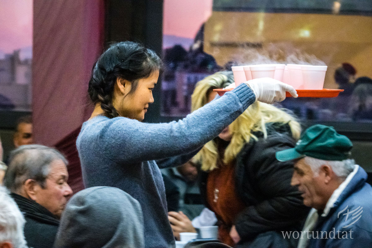 Woman serving hot soup to poor people in Athens - Hellenic Ministries